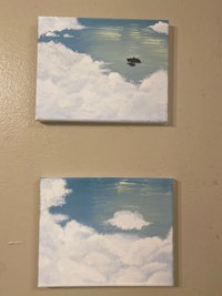 two paintings hanging on a wall with clouds in the background